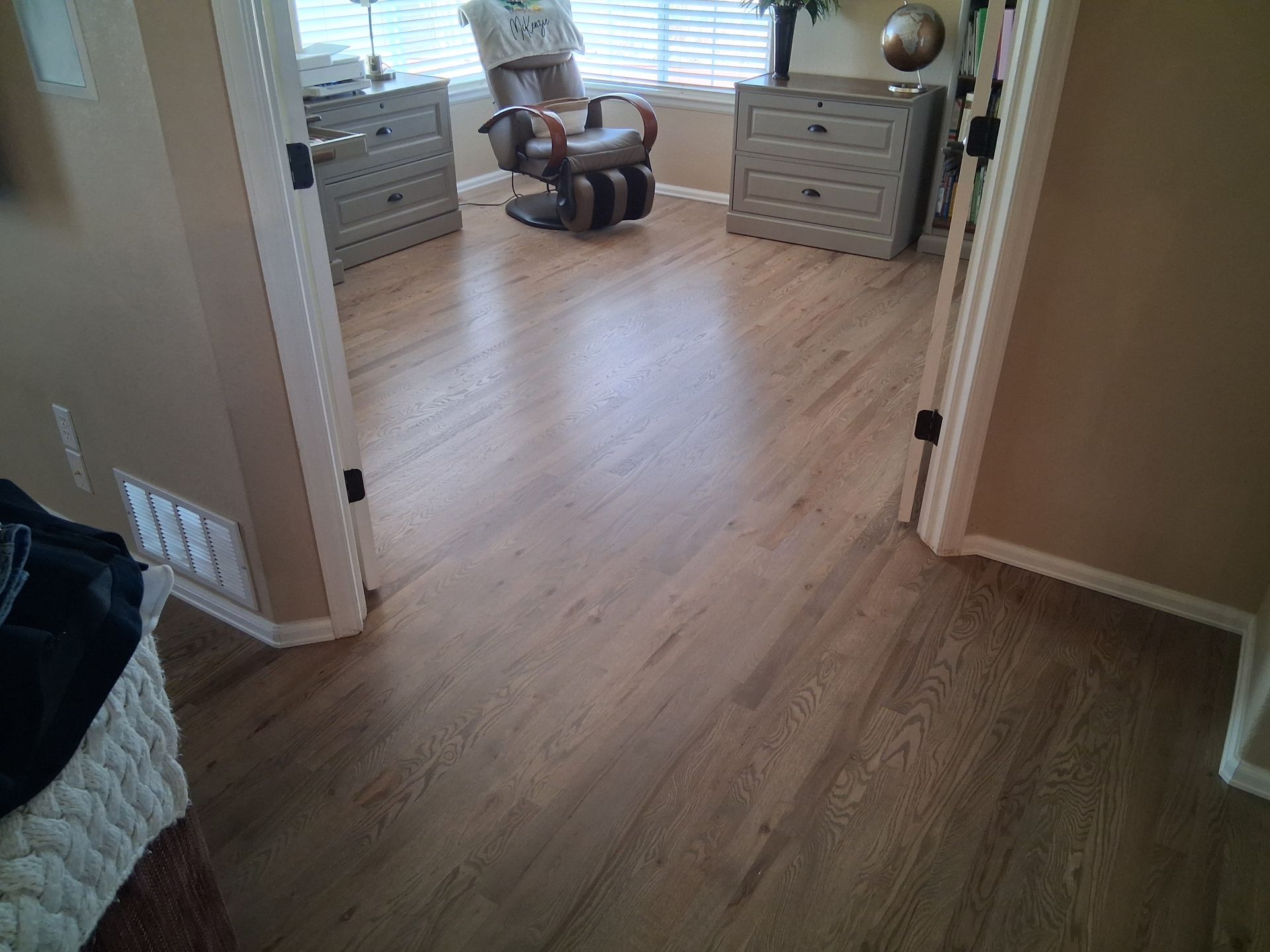 Empty carpeted room with windows, dresser, and exercise equipment in the center.