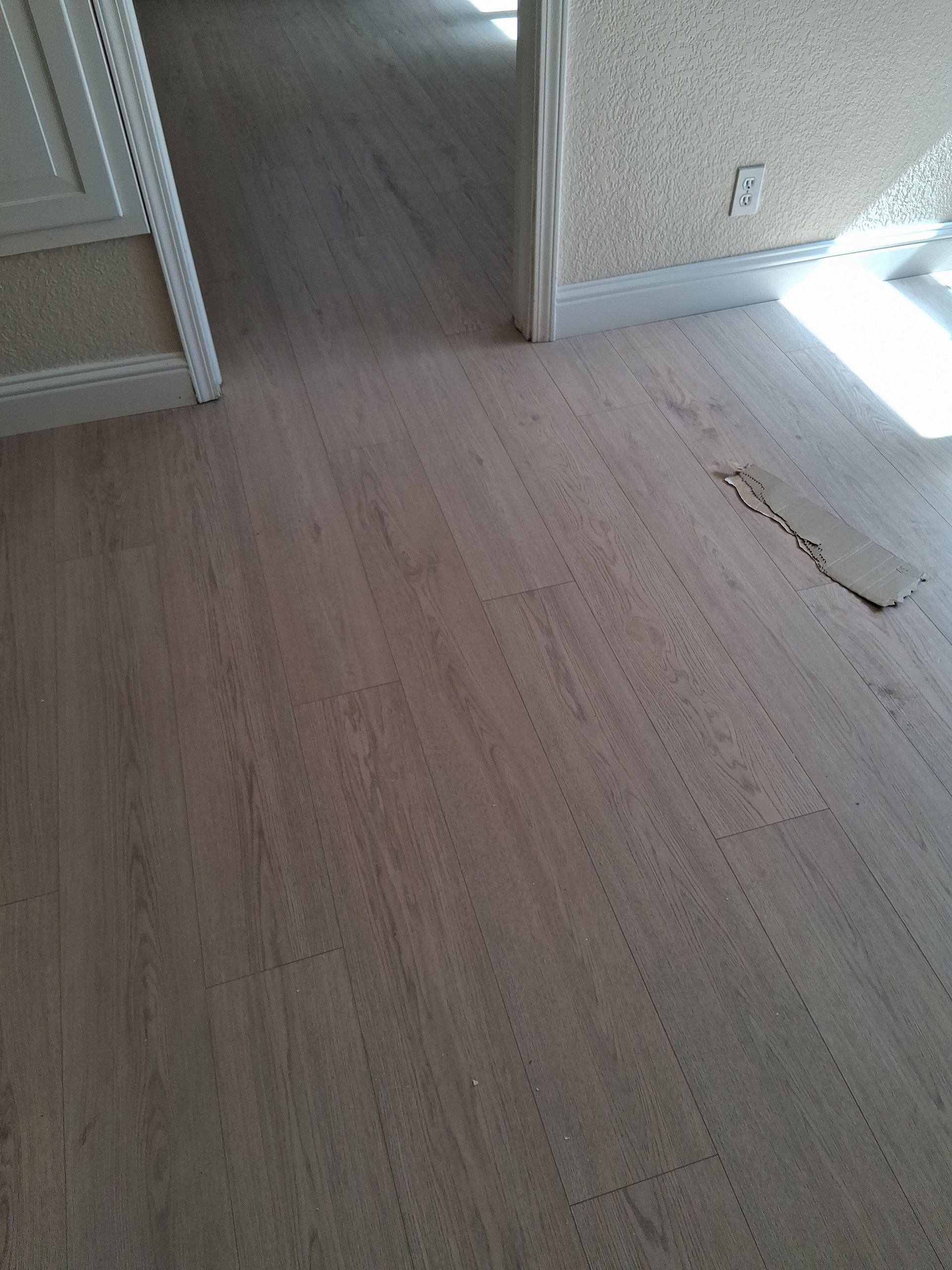 Empty room with light wood flooring, doorway, and sunlight on the wall