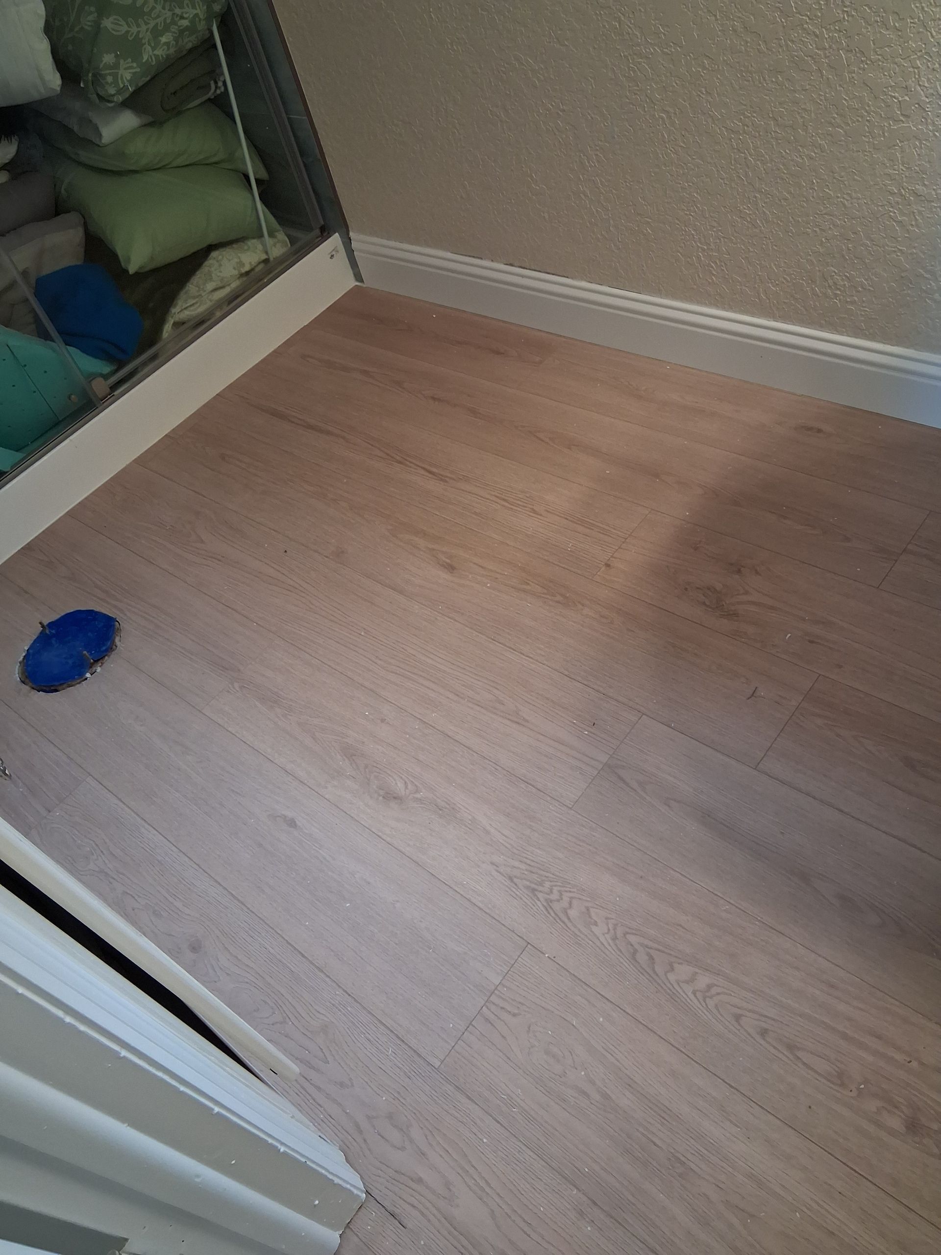 Empty carpeted corner of a room with a blue toy on the floor and shelves of stuffed items to the left