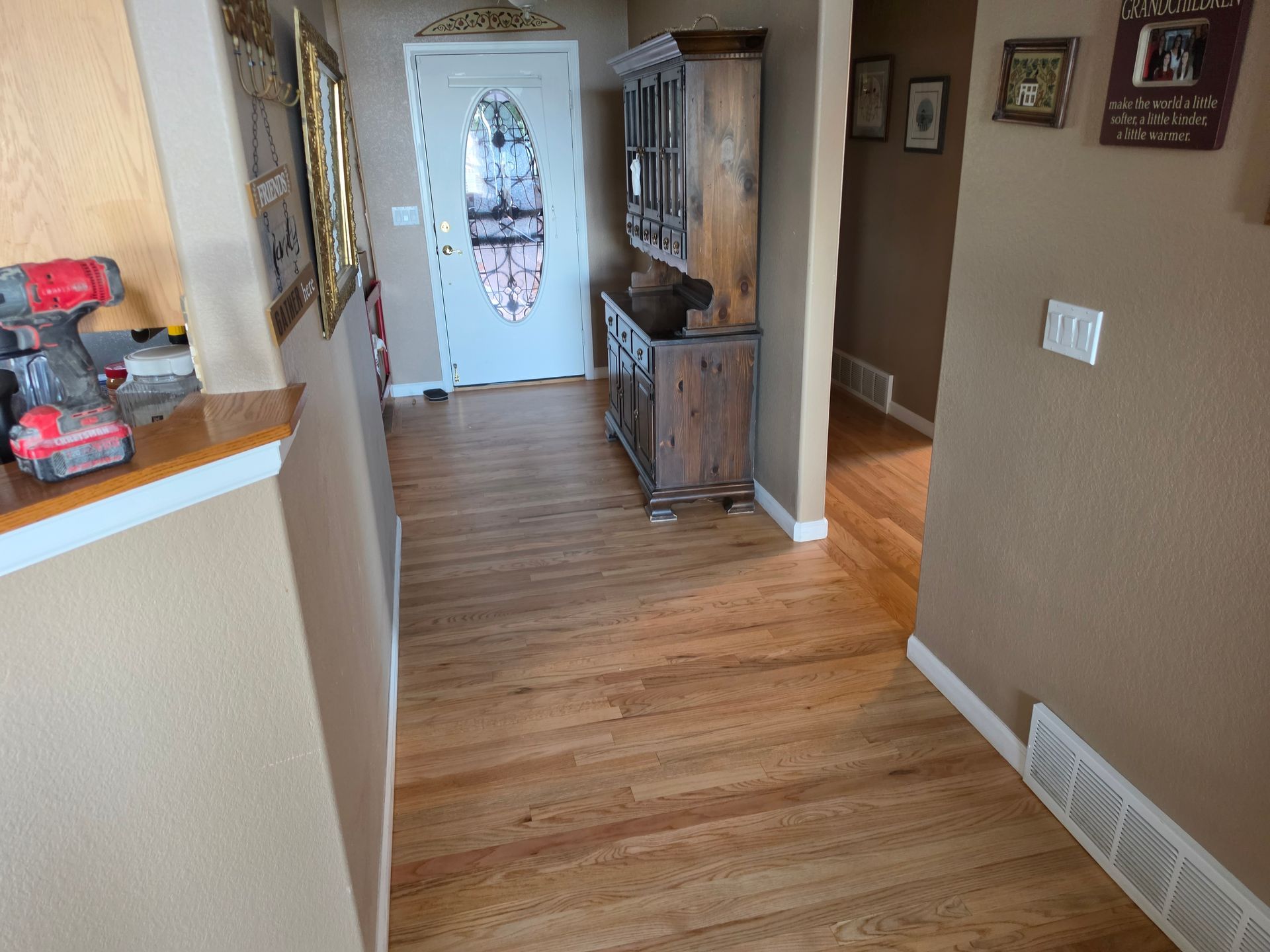 Hallway with hardwood floors, a white front door, a mirror console, and framed wall art.
