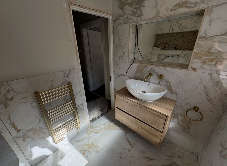 Modern bathroom with two navy vanities, round mirrors, and a central walk-through doorway