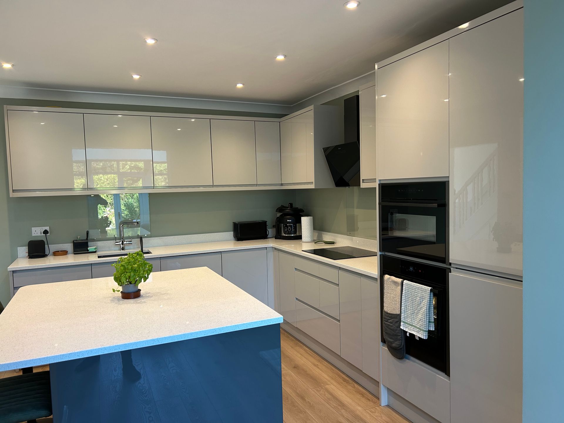 Modern white kitchen with island, built-in oven, and glossy cabinets