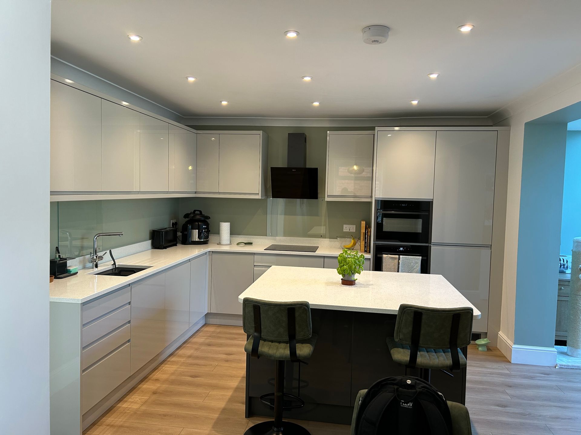 Modern white kitchen with island, recessed lights, and built-in oven and refrigerator