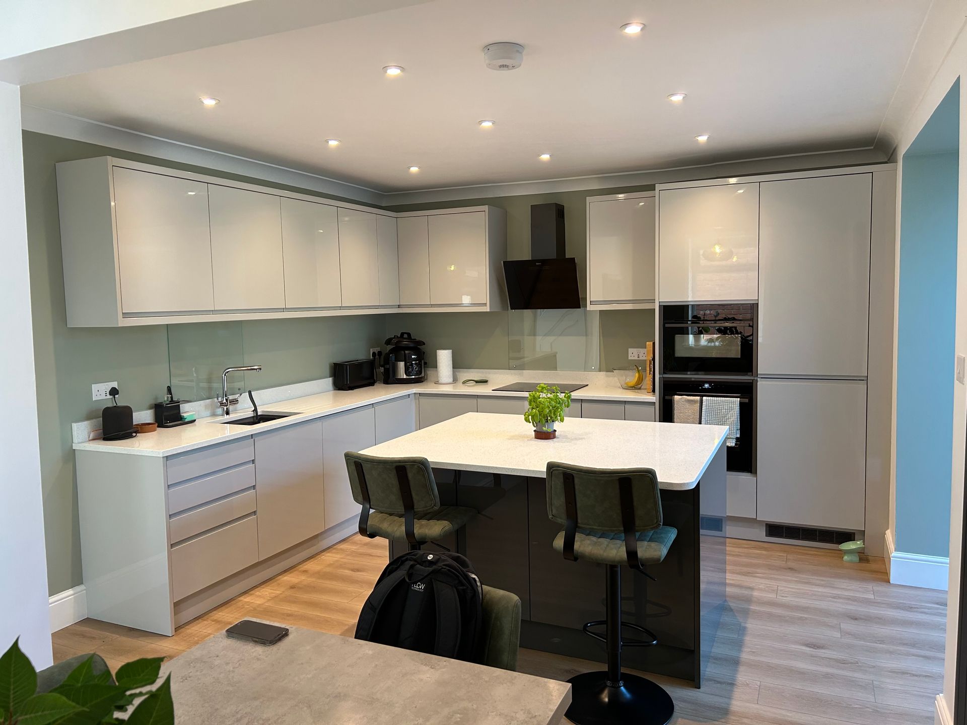 Modern white kitchen with island, gray cabinetry, stainless appliances, and wood floor