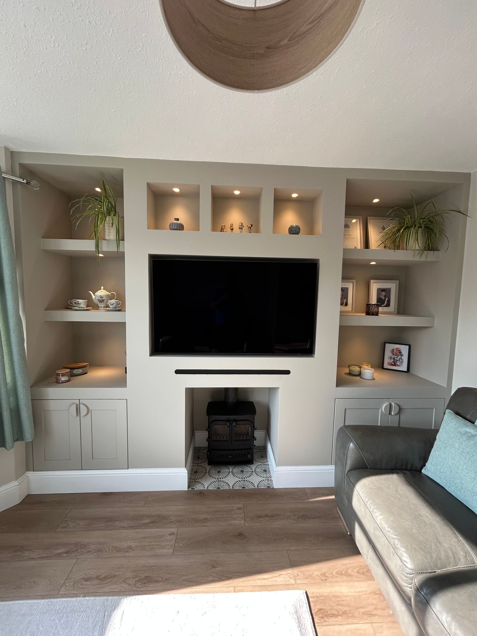 Living room wall with recessed shelves, TV, and fireplace in a neutral-toned interior.