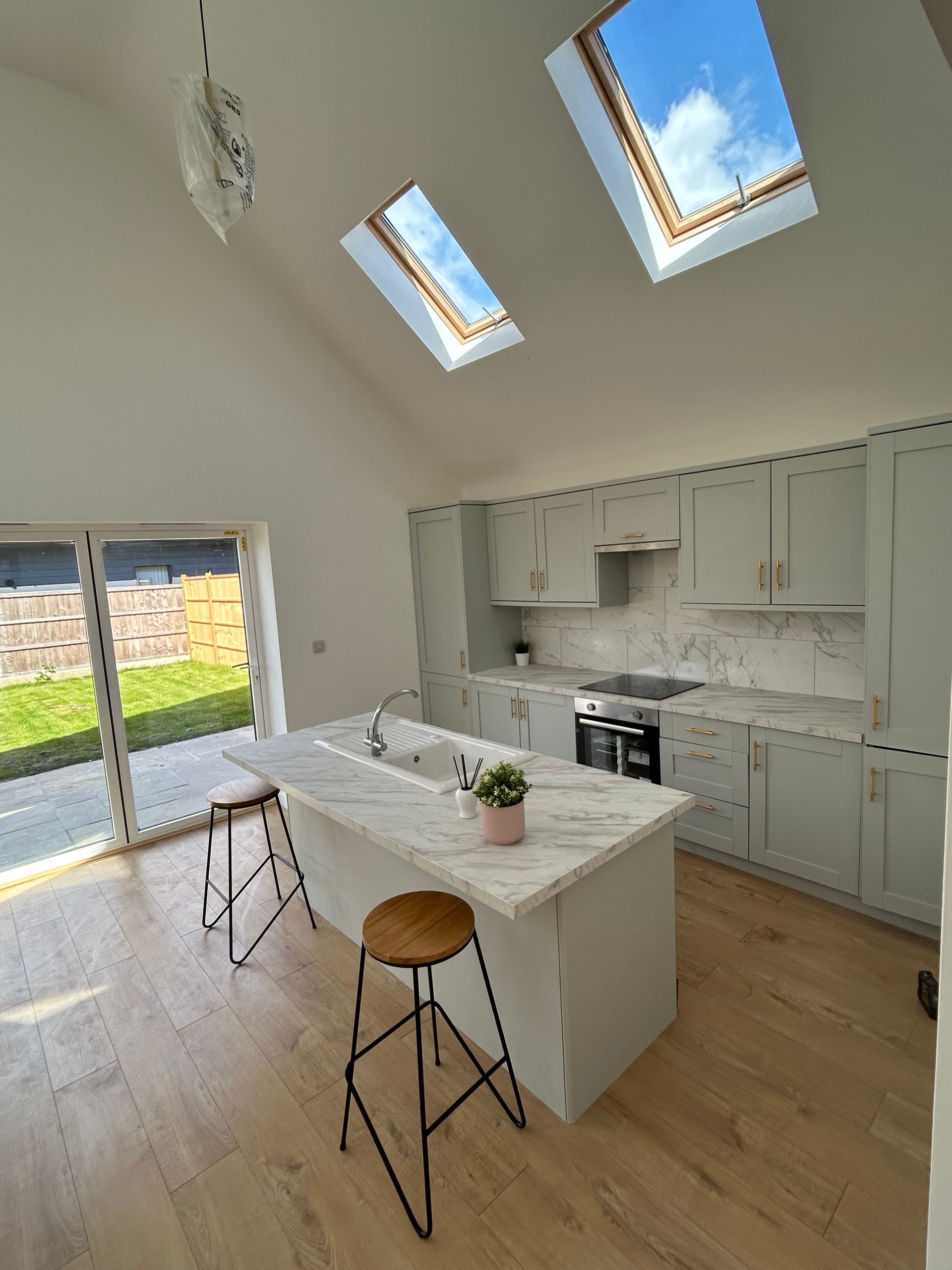 Bright modern kitchen with island, skylights, wood floor, and sliding glass door to yard