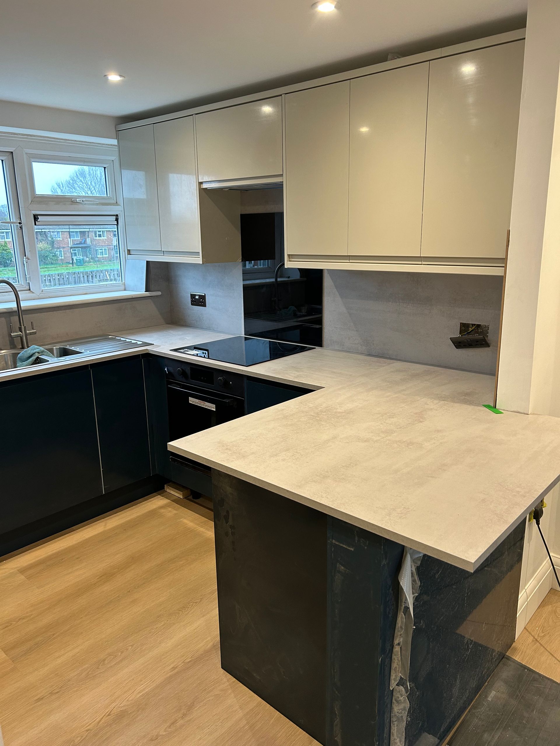 Modern kitchen with white cabinets, black lower cabinets, and light stone countertops.