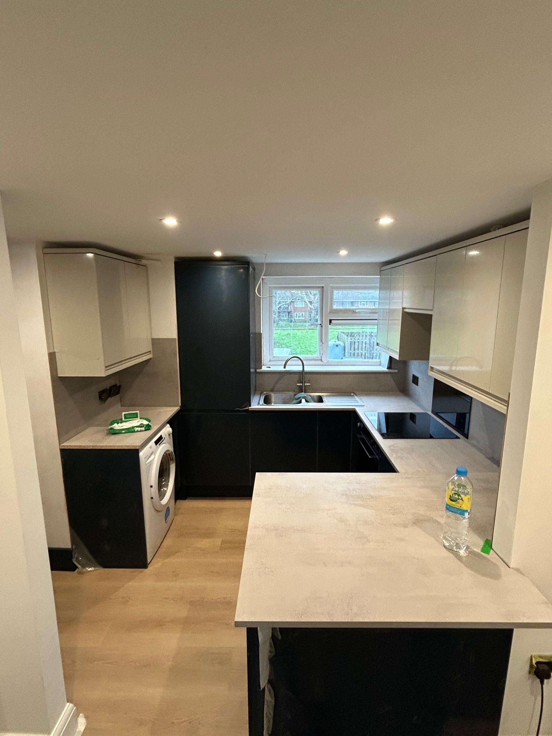 Modern kitchen with black cabinets, beige island, and a window over the sink