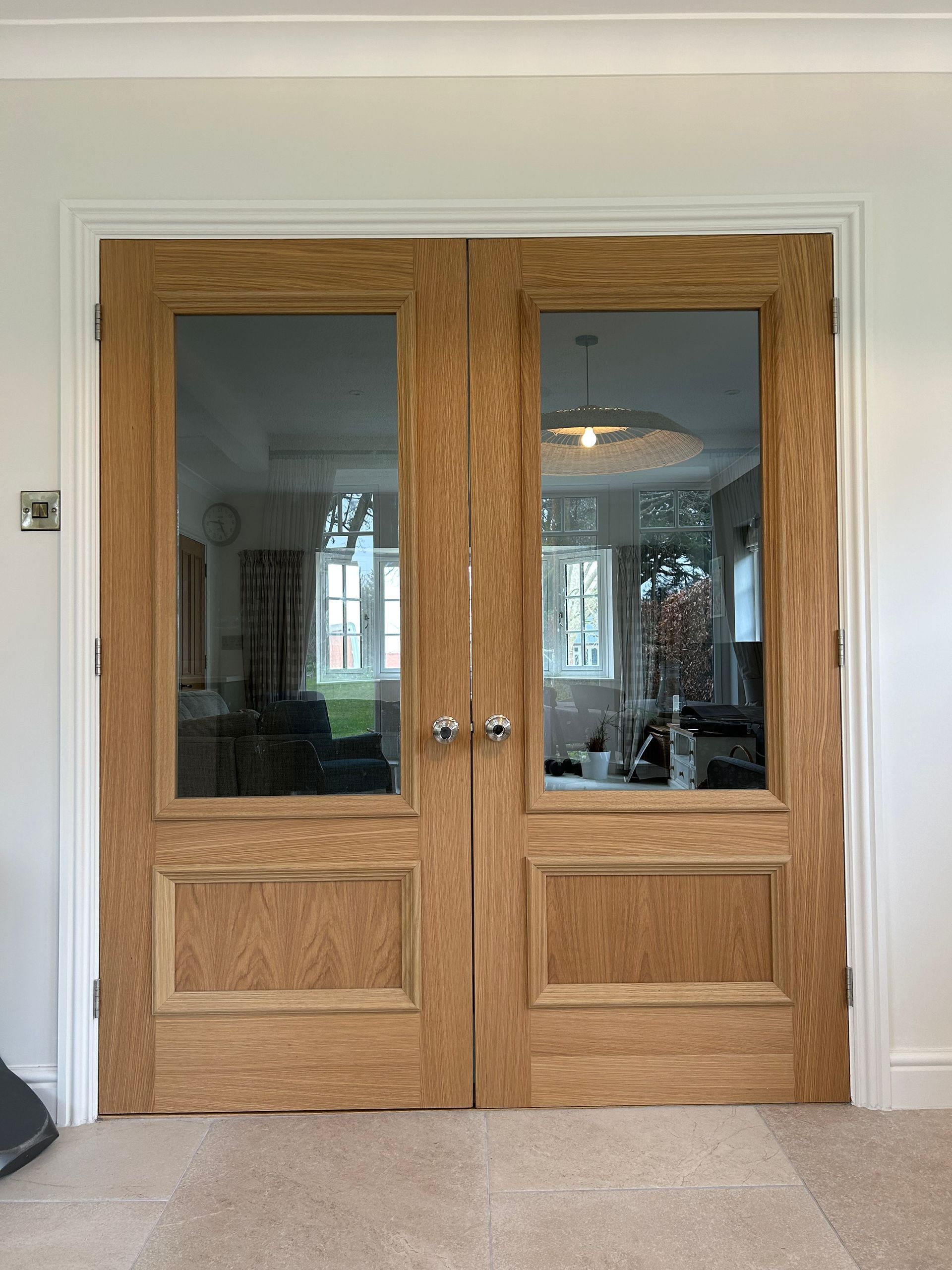 Wooden double interior doors with glass panes and brass knobs in a home hallway