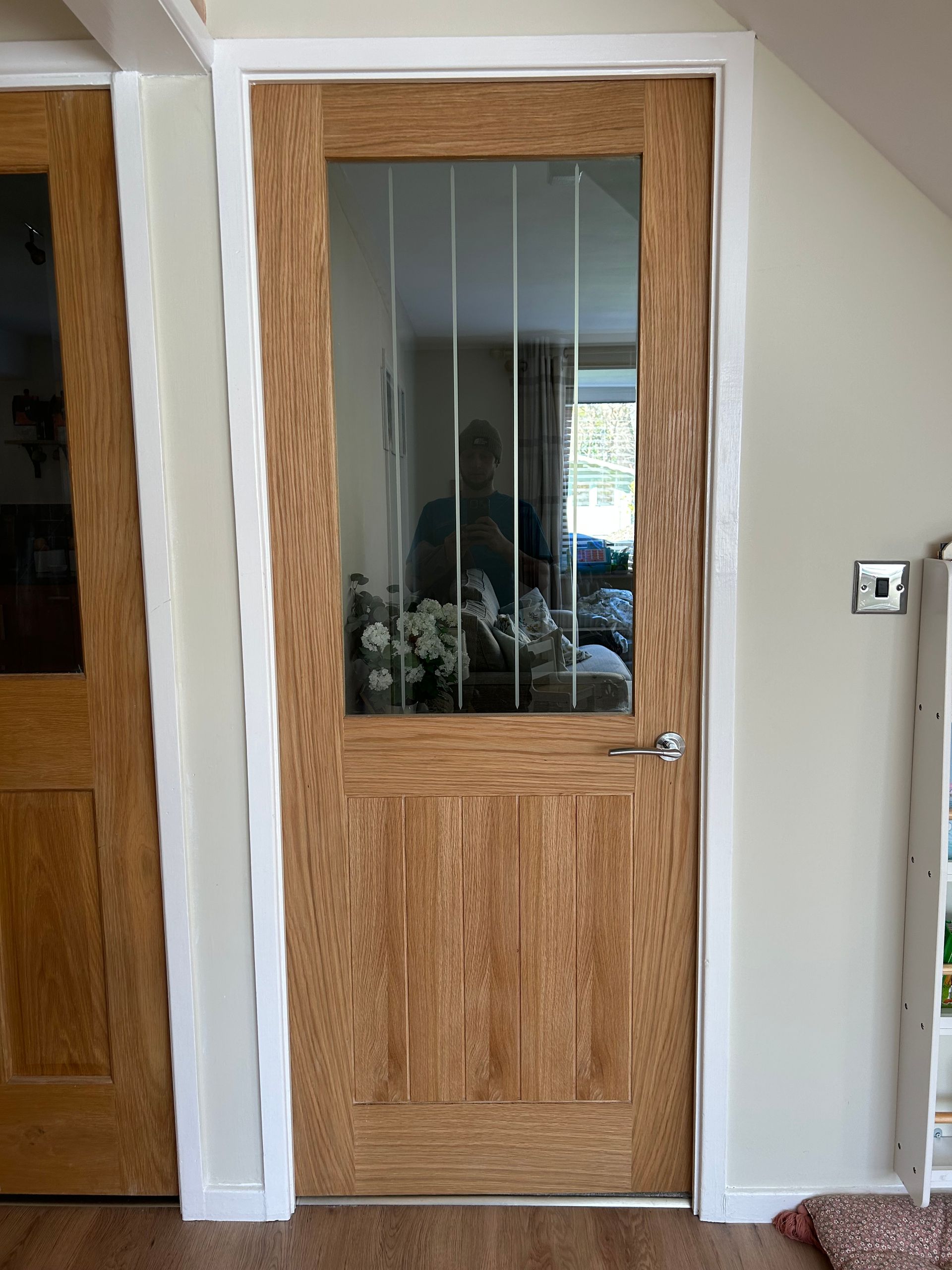 Wooden interior door with glass panes beside a light switch in a hallway