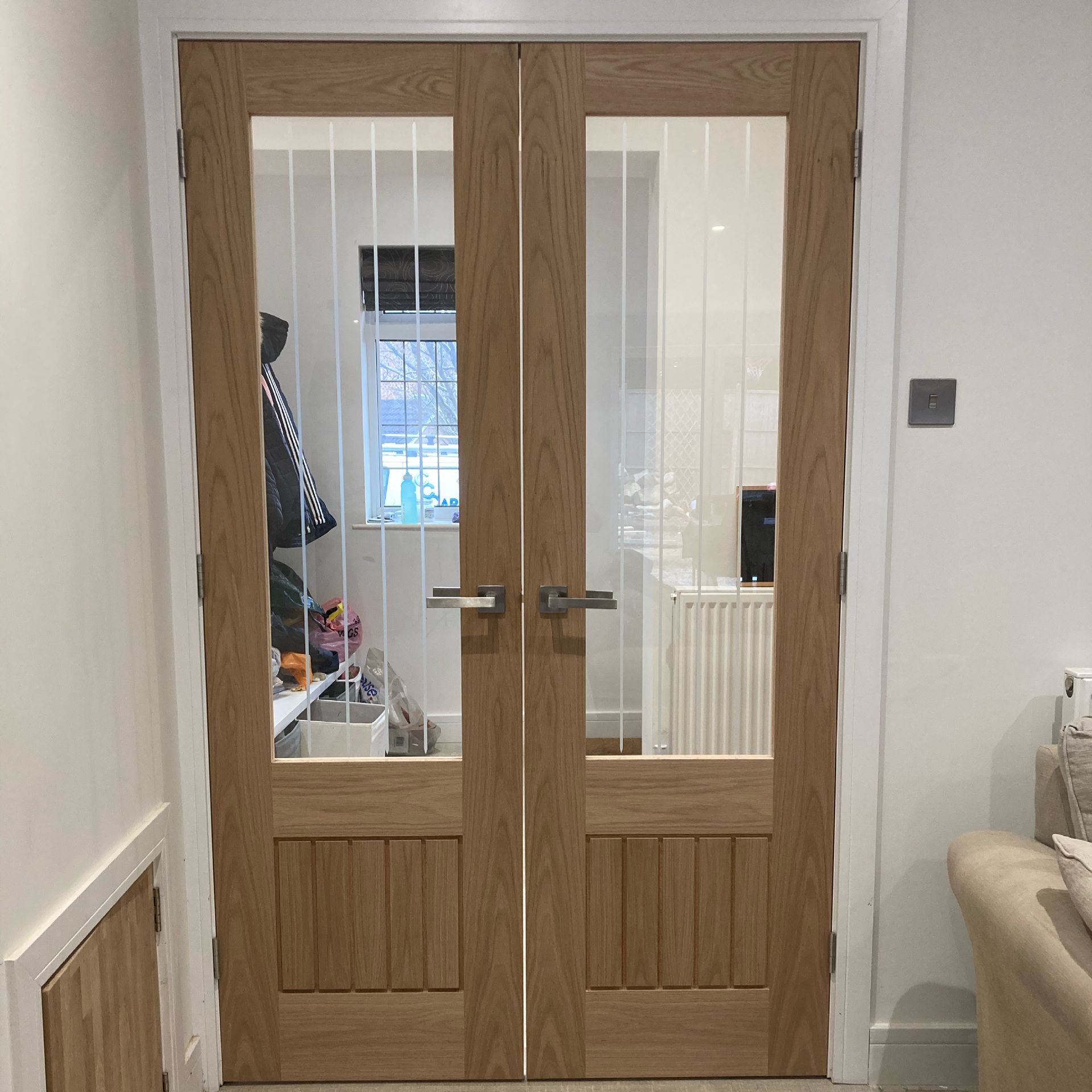 Double wooden glass-panel doors opening into a bright room with white walls and a radiator.