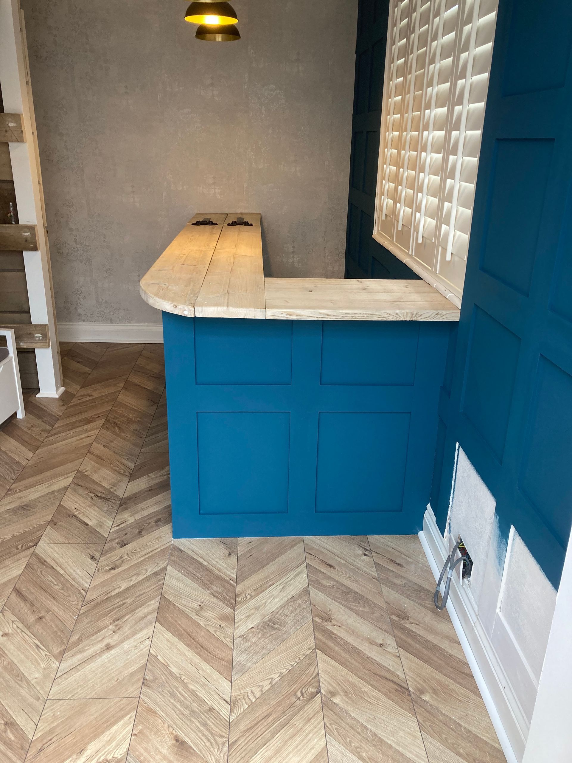Blue kitchen island with light stone countertop in a herringbone-floored room