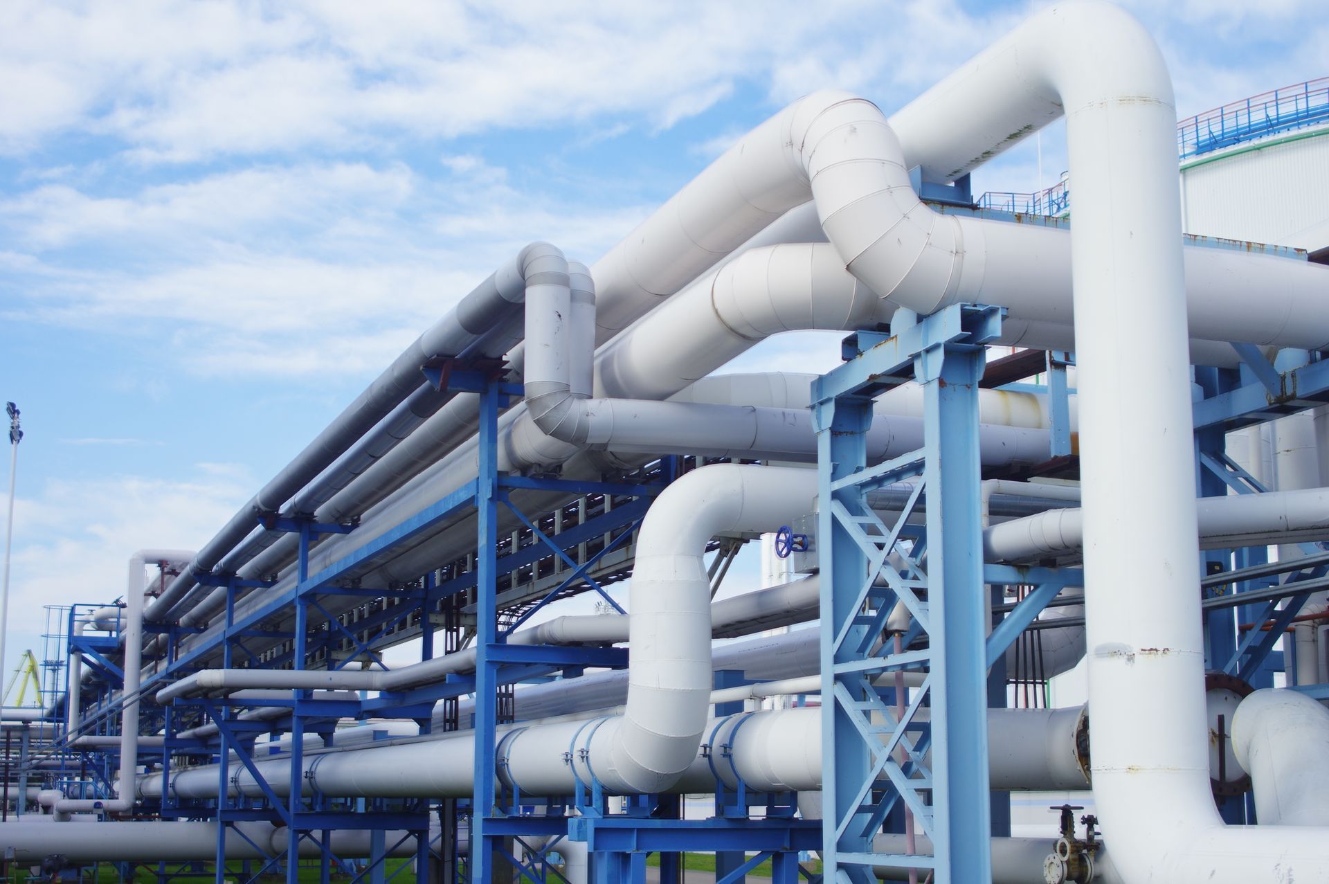 Tuberías industriales blancas sobre soportes azules contra un cielo azul.