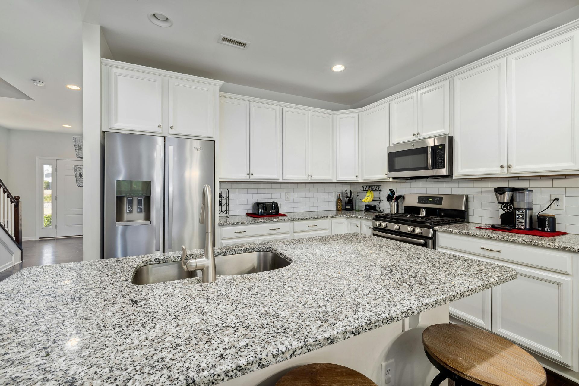 White kitchen with granite countertops, stainless steel appliances, and white cabinets.