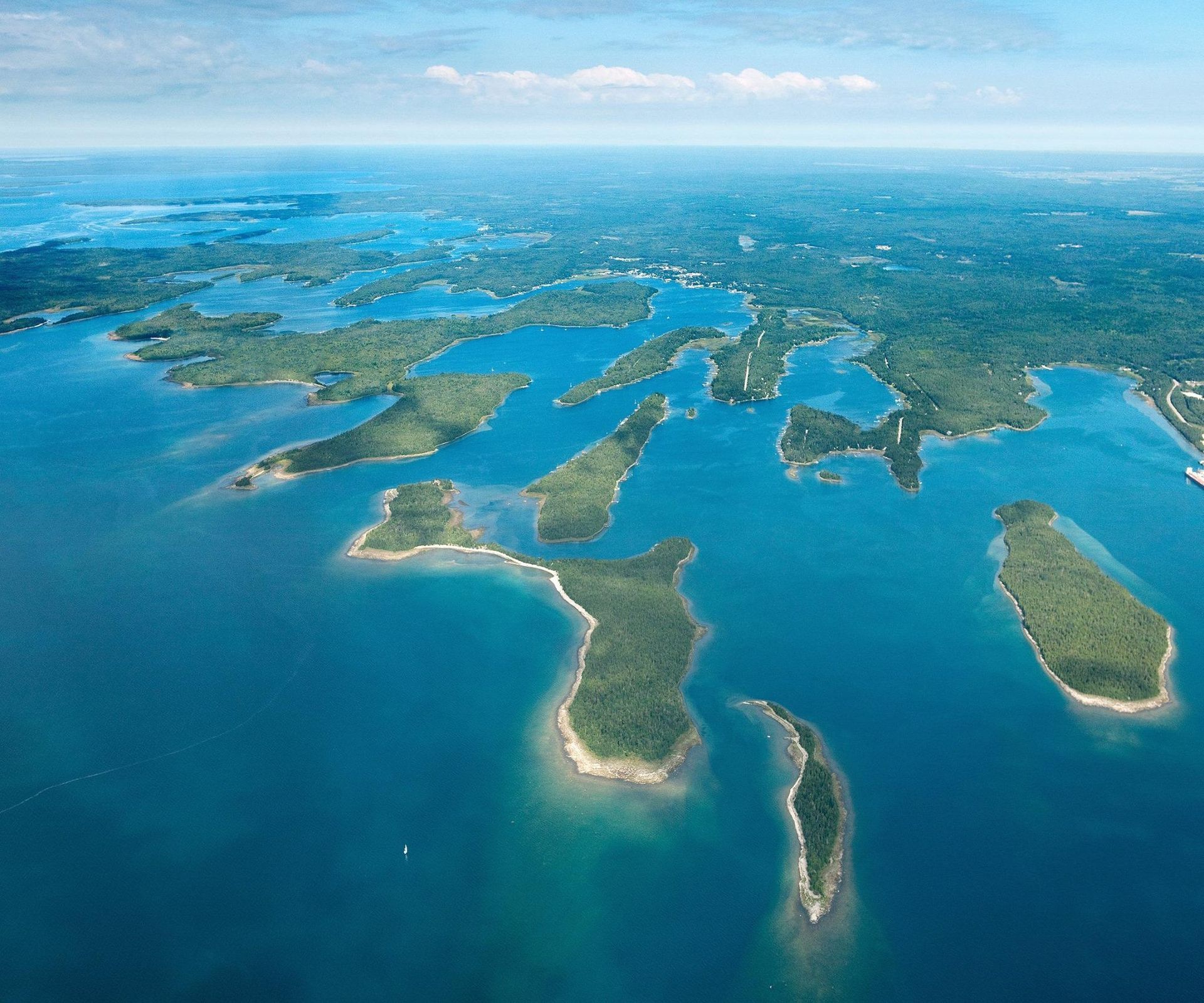 Aerial view of blue ocean with green islands and sandy shores under a clear sky