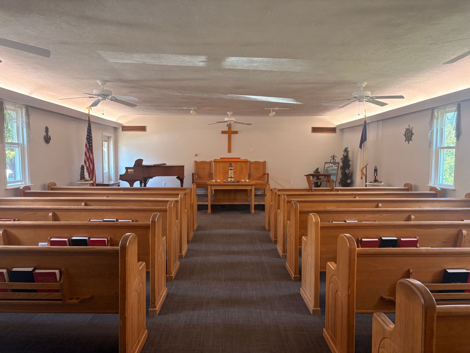 Empty church sanctuary with wooden pews, piano, and altar under a cross