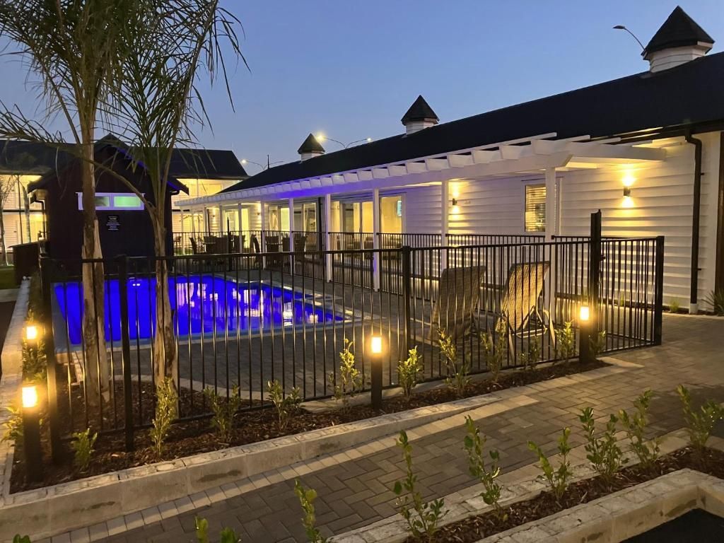 A large swimming pool is surrounded by a fence in front of a building.