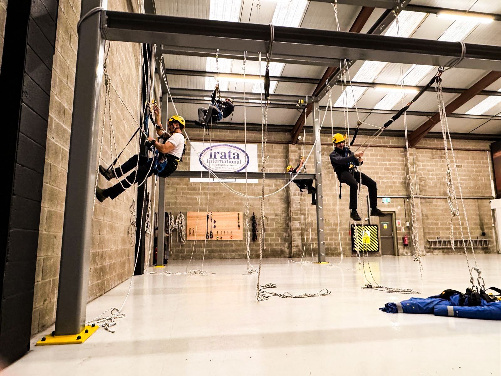 Industrial rope access training at dangle academy in Belfast. Four students on ropes in yellow helmets.