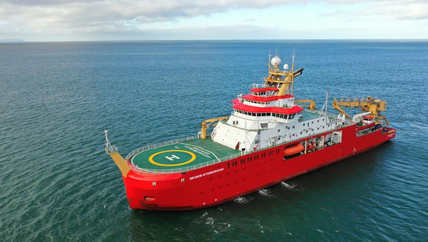 An aerial view of a large red ship in the ocean.