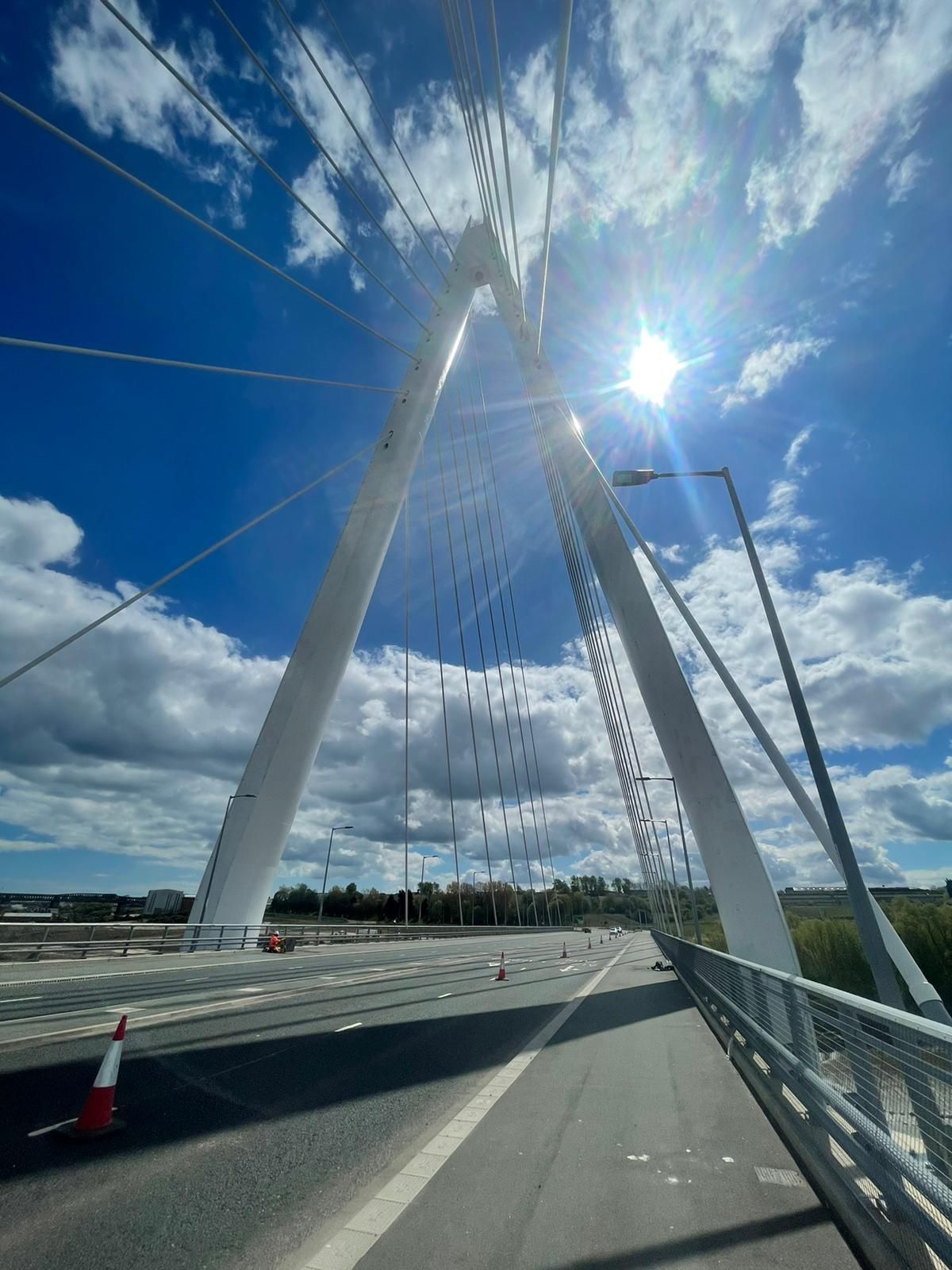 The sun is shining through the clouds on a bridge