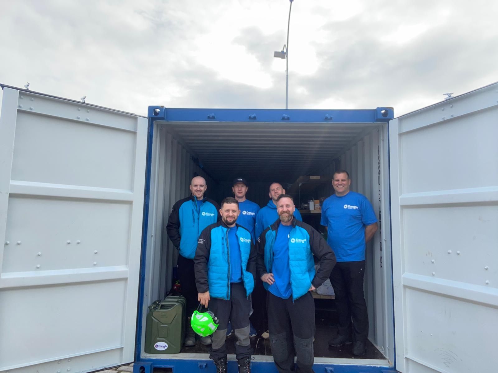 A group of men are standing in a shipping container.