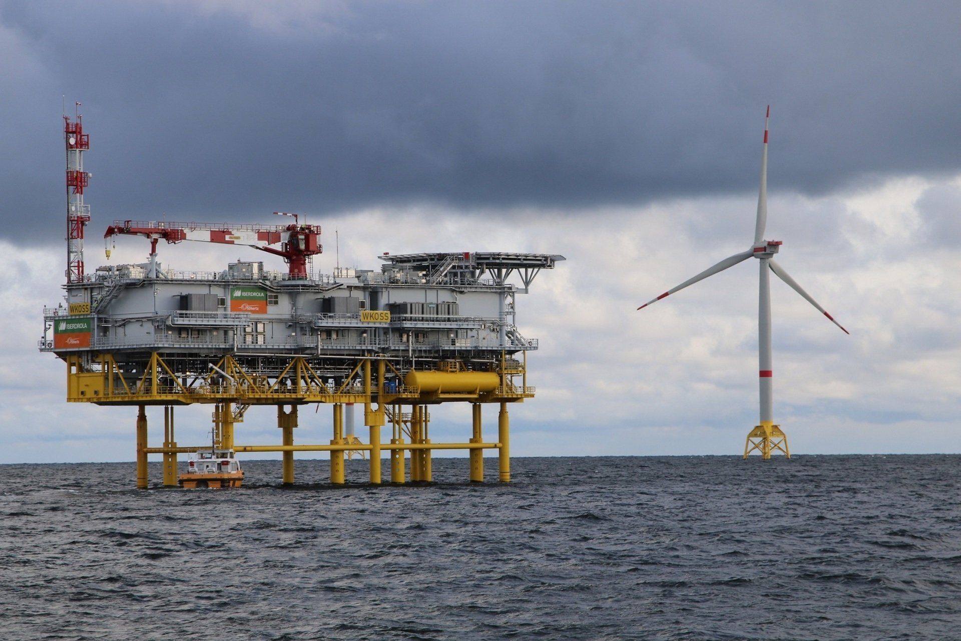 Offshore platform and wind turbine in the ocean under a cloudy sky.