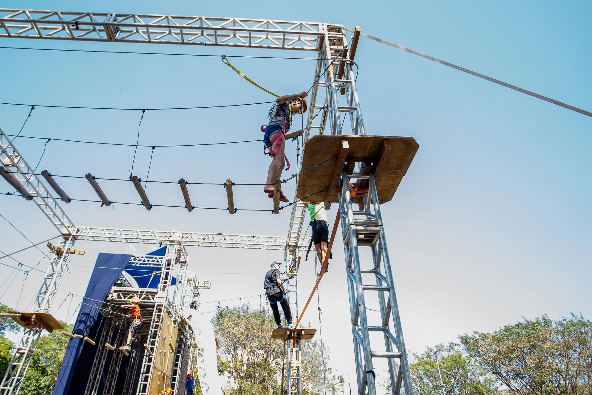 People on a high ropes course, traversing obstacles like ropes, bridges, and ladders.