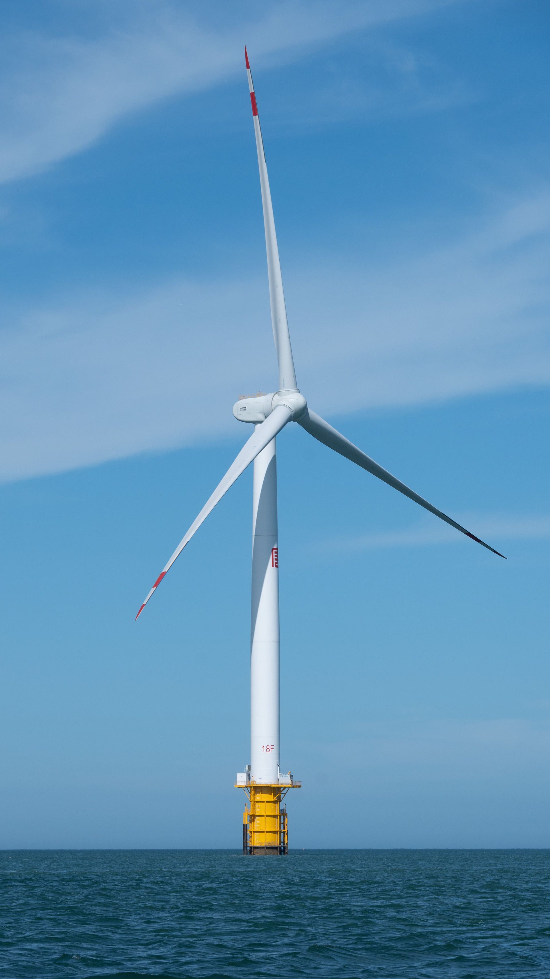 Offshore wind turbine in the ocean under a blue sky