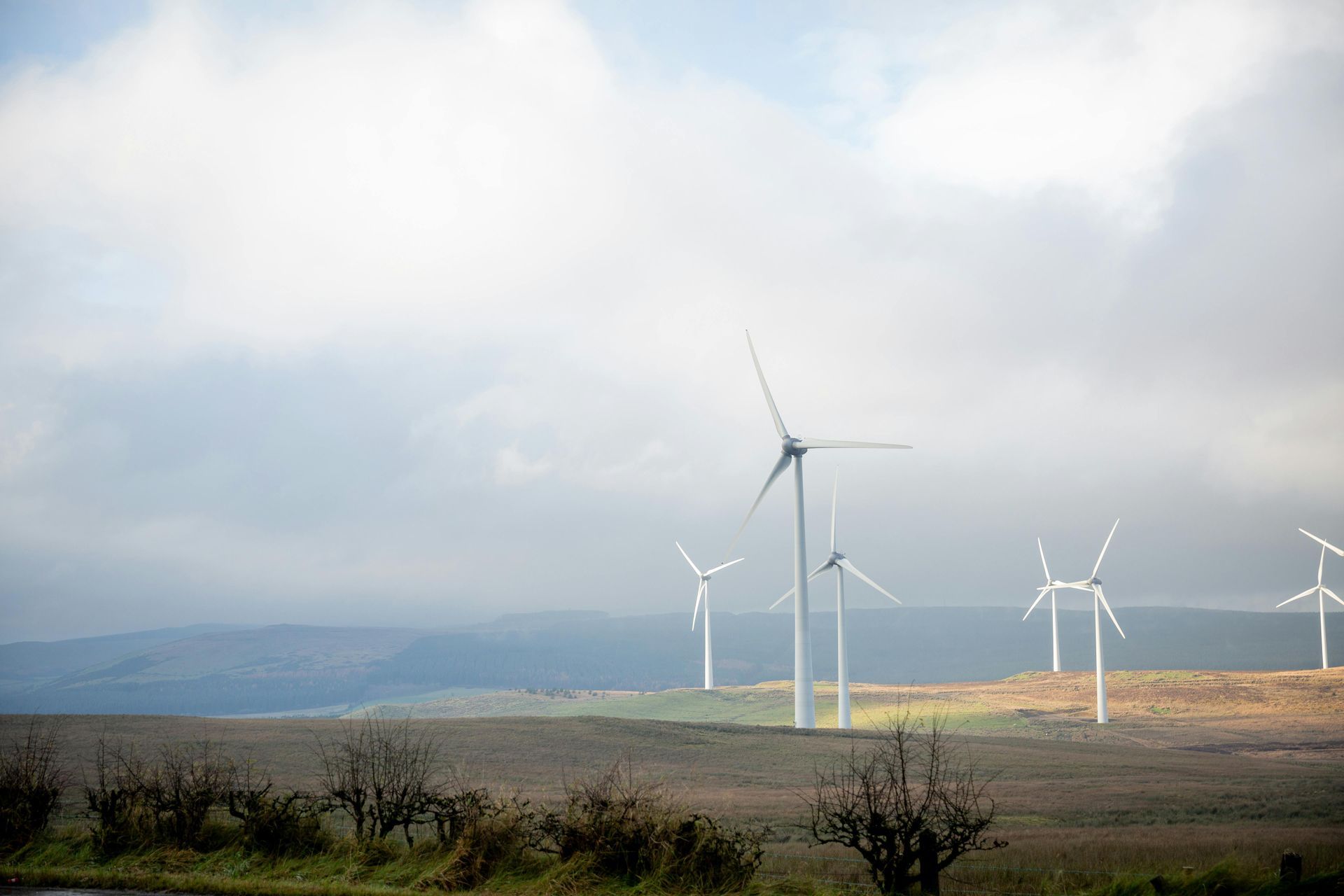 Wind turbines on a hillside under cloudy skies.