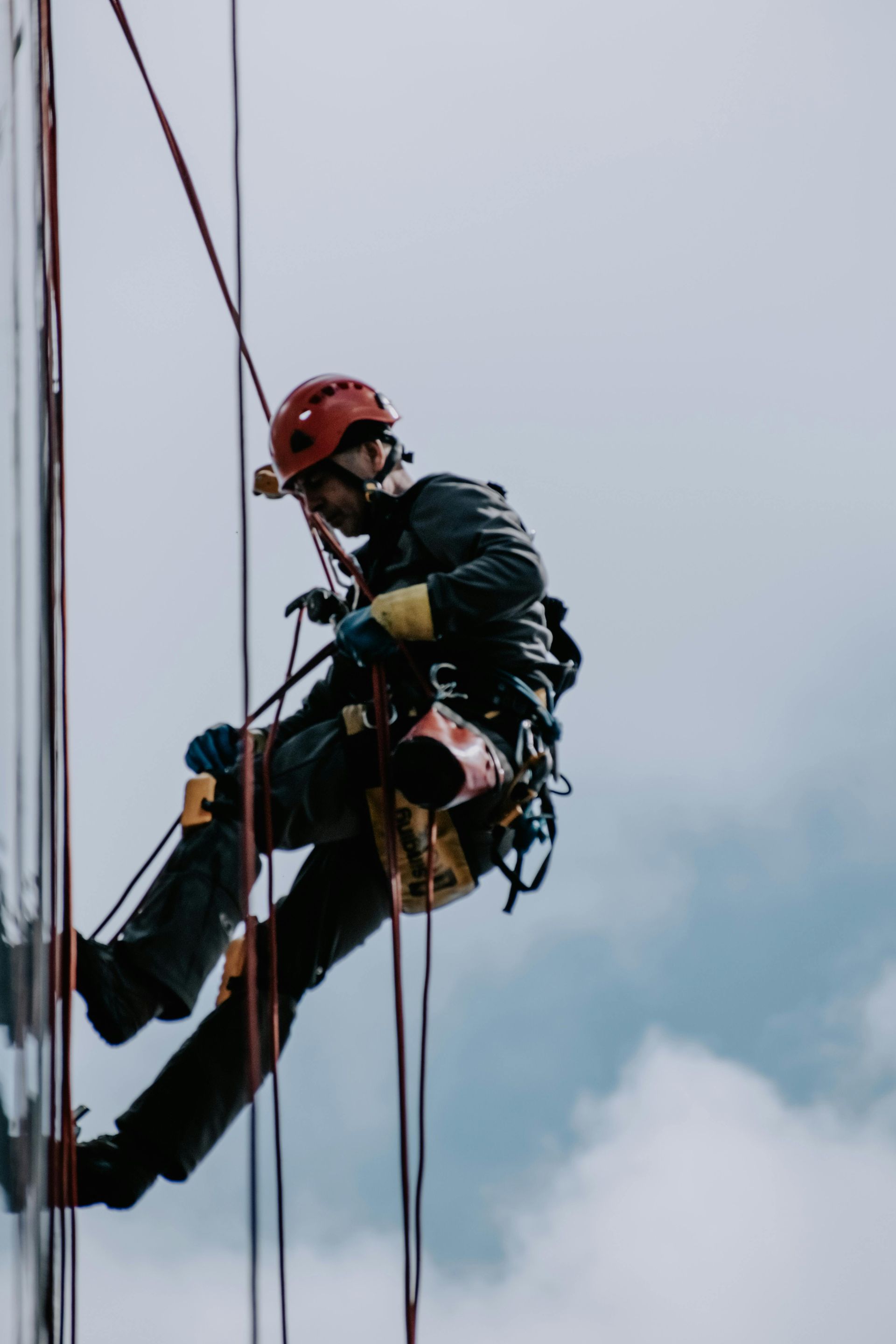 A man is climbing a tall building with a rope.
