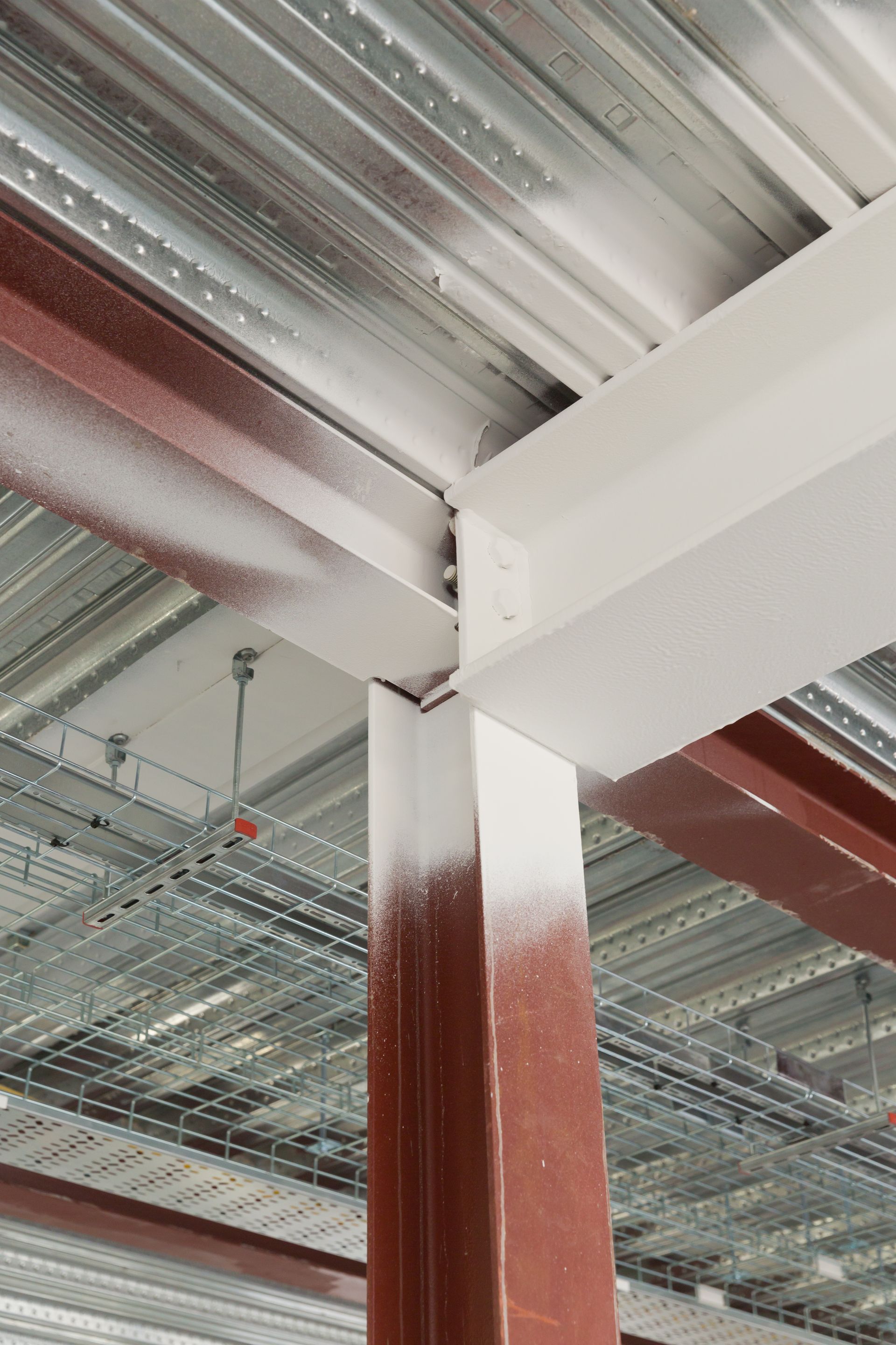 Steel beams and metal decking in a construction site, partly painted white and red-brown.