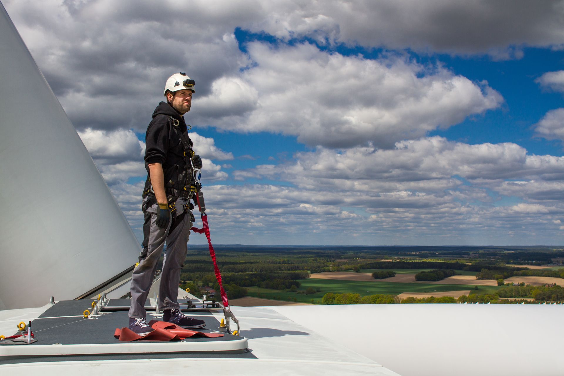 A man is standing on top of a wind turbine.