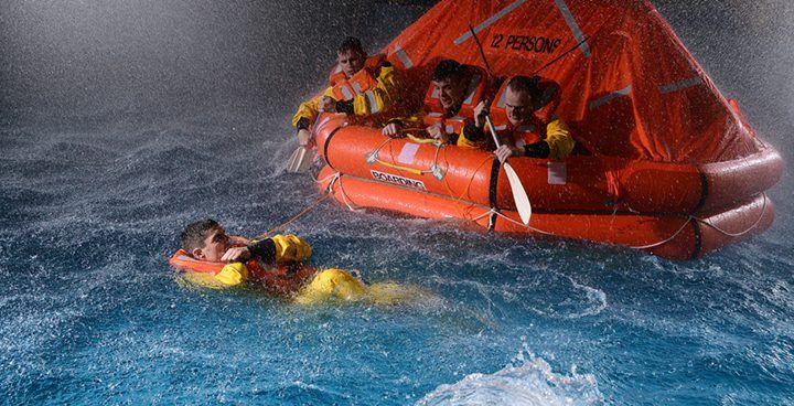A group of people are in an orange raft in the water.