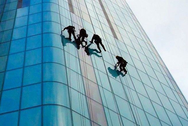 Several climbers rappelling down a glass office building facade