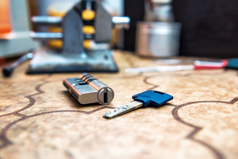 Blue Key Is Laying On A Wooden Table Besides A Lock — Ontime Locksmiths & Security In Mullumbimby, NSW