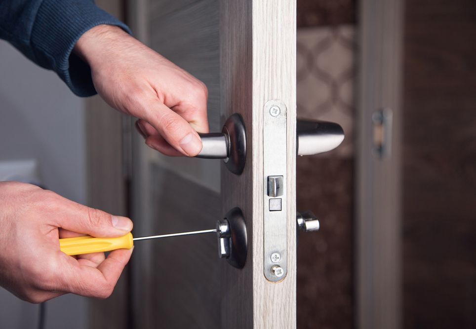 Man Is Fixing A Door With A Yellow Screwdriver — Ontime Locksmiths & Security In Brunswick Heads, NSW