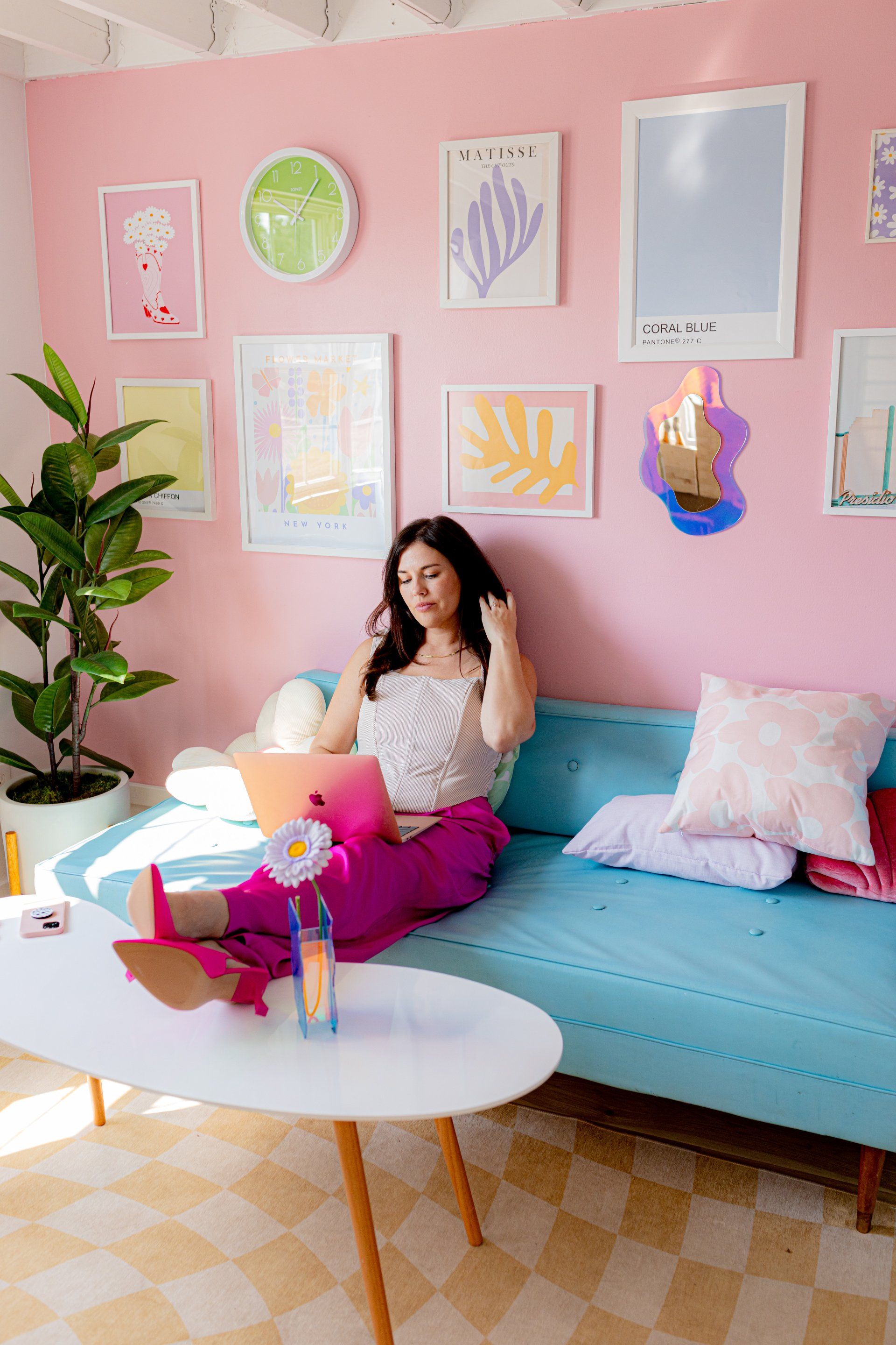 Jordan sitting on a blue couch working on her laptop