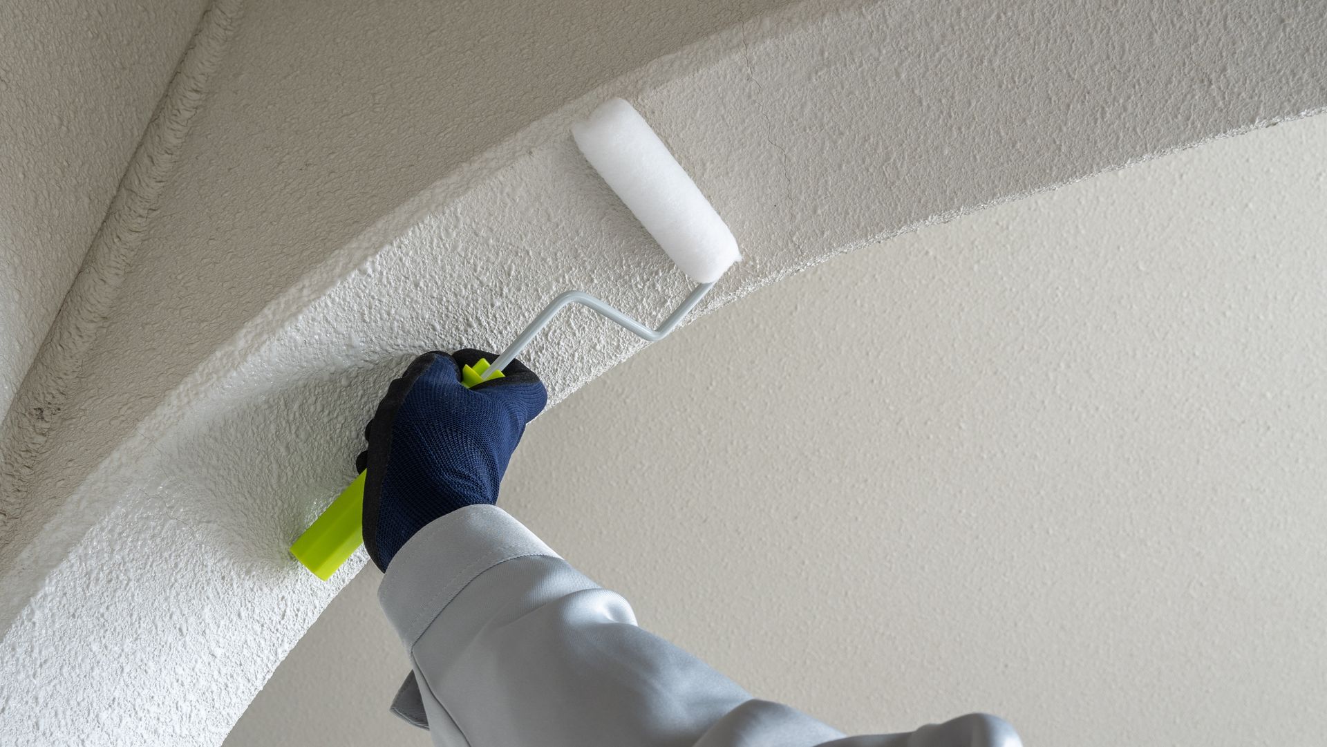 A person is painting a wall with a roller.