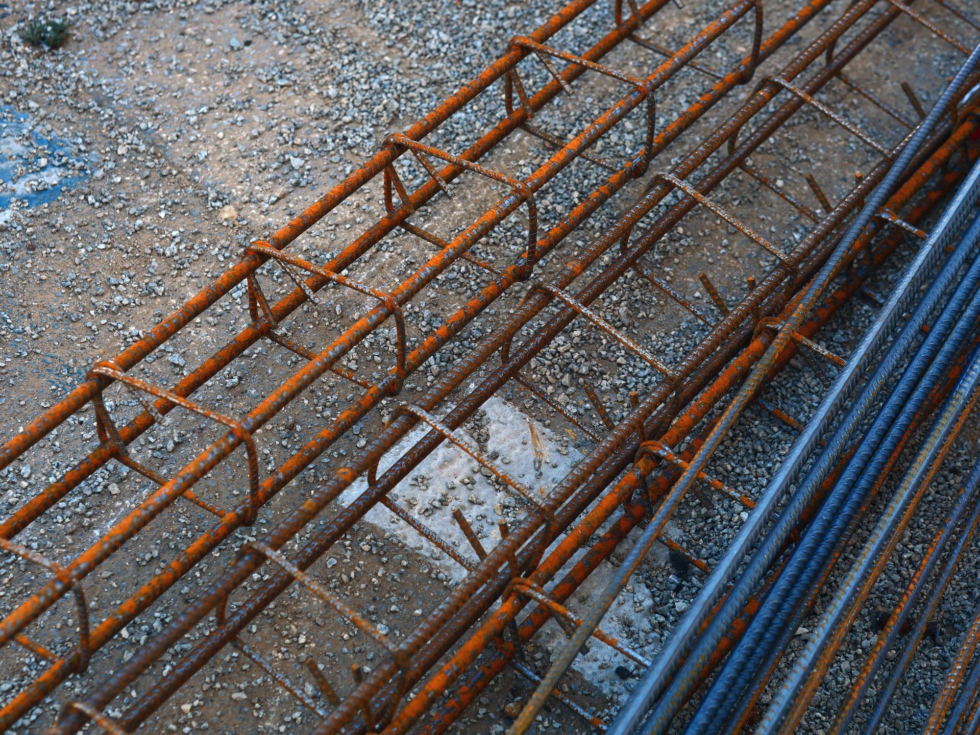 A bunch of rusty metal bars are laying on the ground.