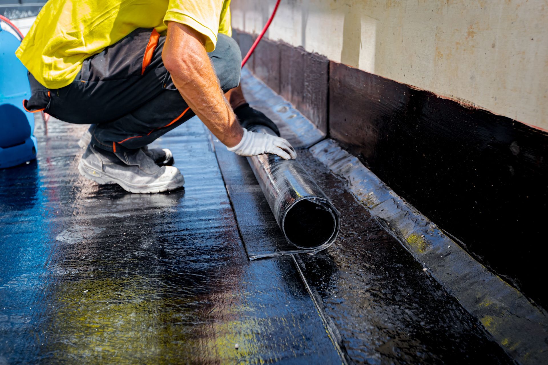 A man is kneeling down on the ground holding a pipe.