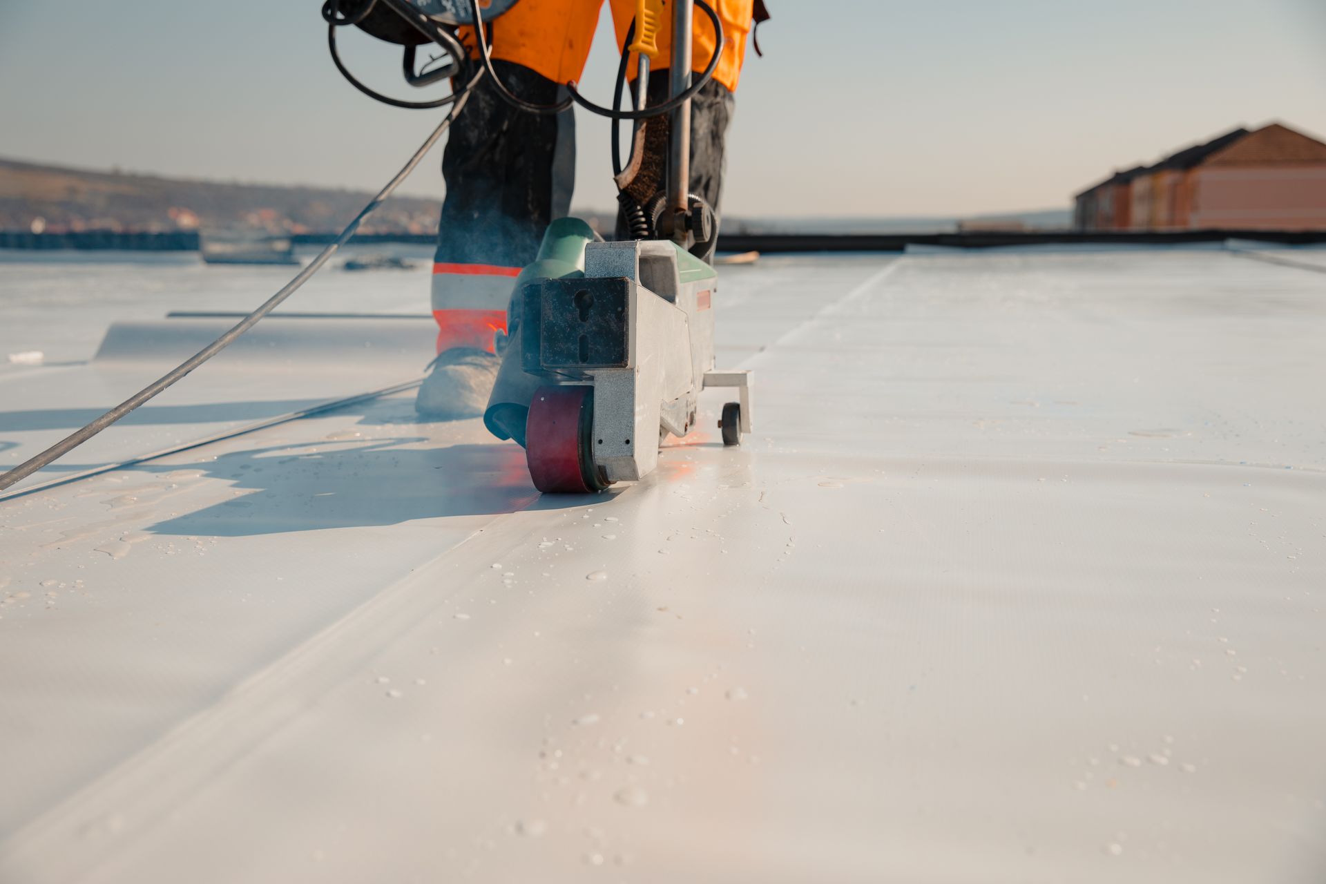 A man is using a machine to seal a roof.
