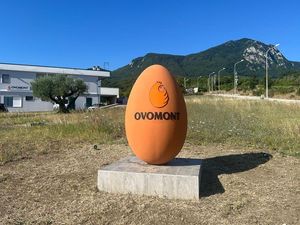 Una statua arancione a forma di uovo con la scritta