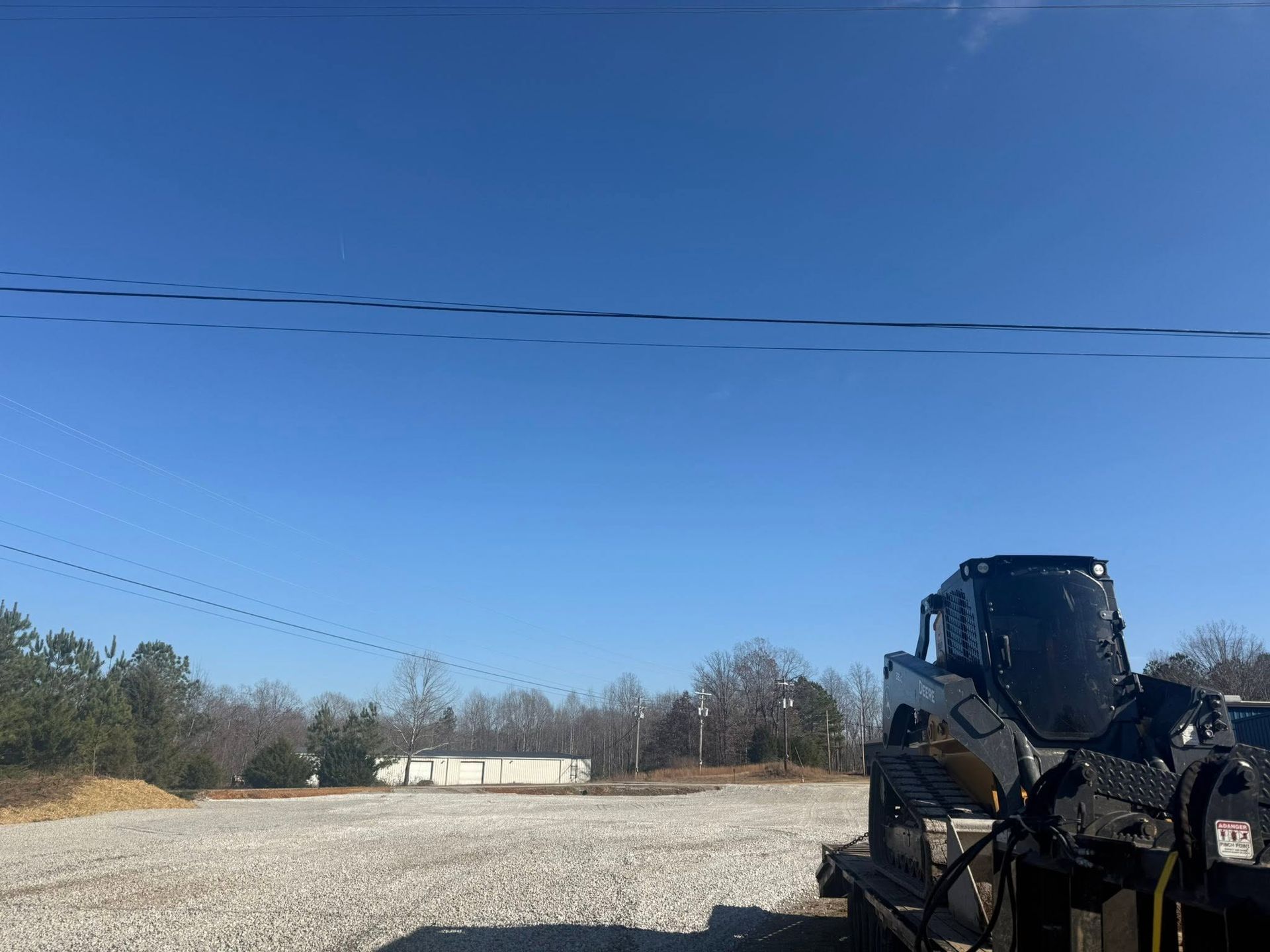 Black off-road vehicle parked on a gravel lot under a clear blue sky