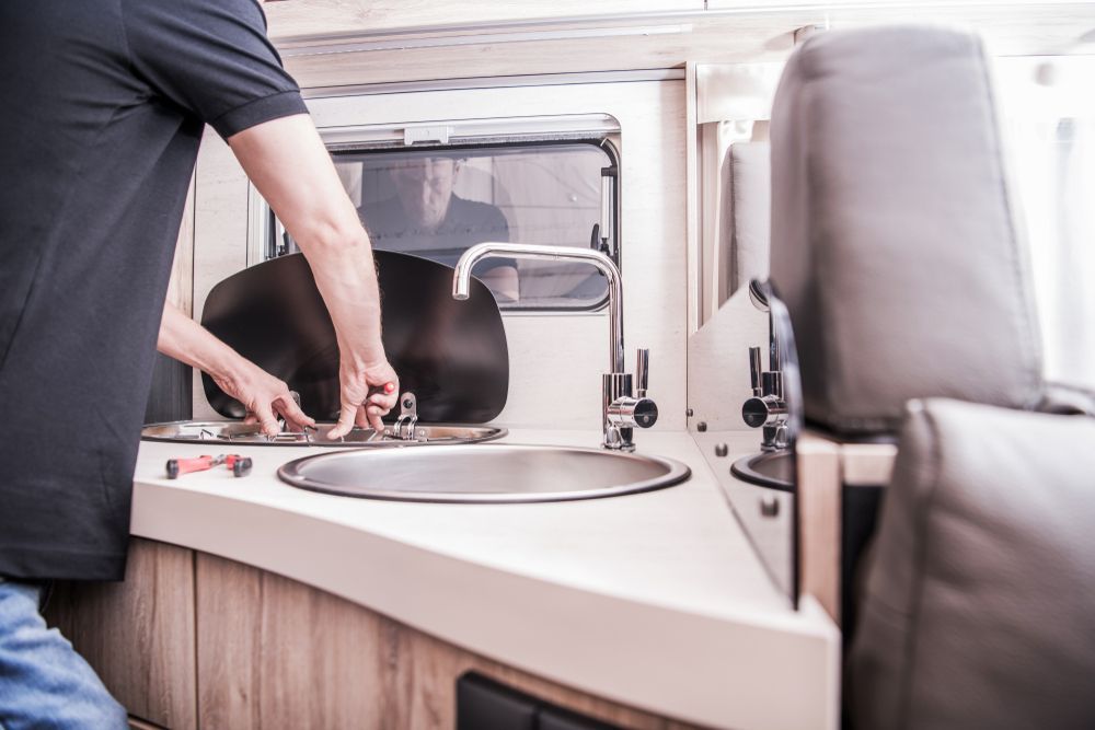 A Man Is Fixing A Sink In A Camper Van — Cairns Clear Water Company In Westcourt, QLD