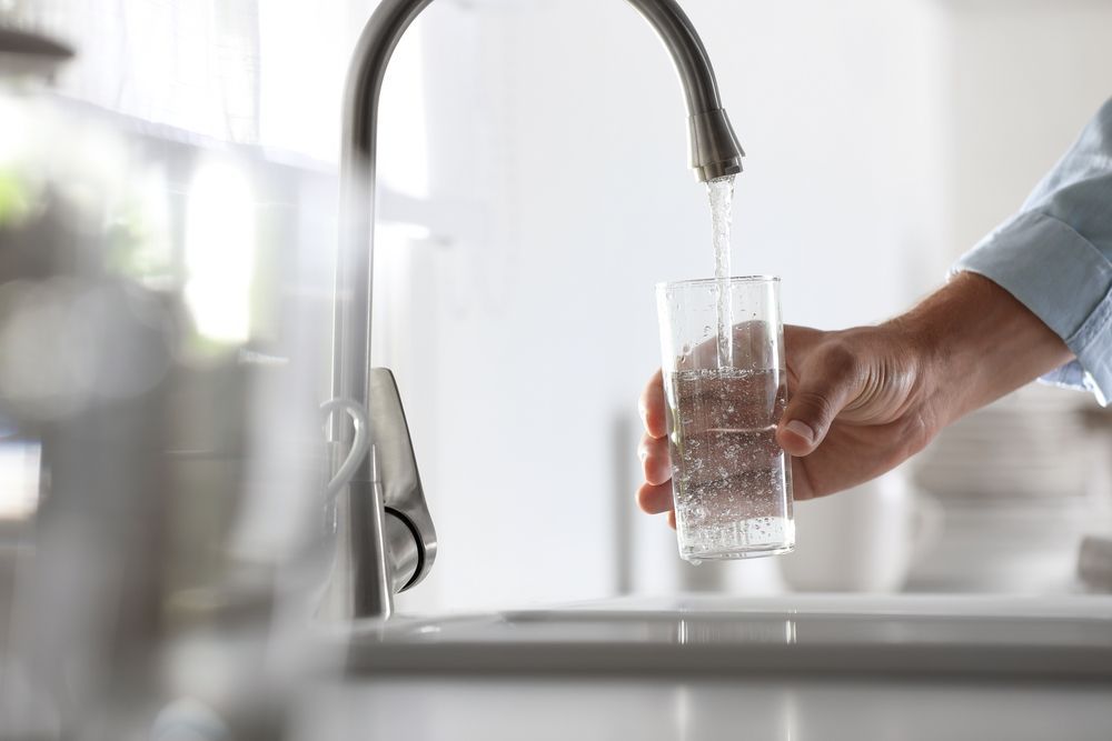 A Person Is Pouring Water From A Faucet Into A Glass — Cairns Clear Water Company In Tablelands, QLD