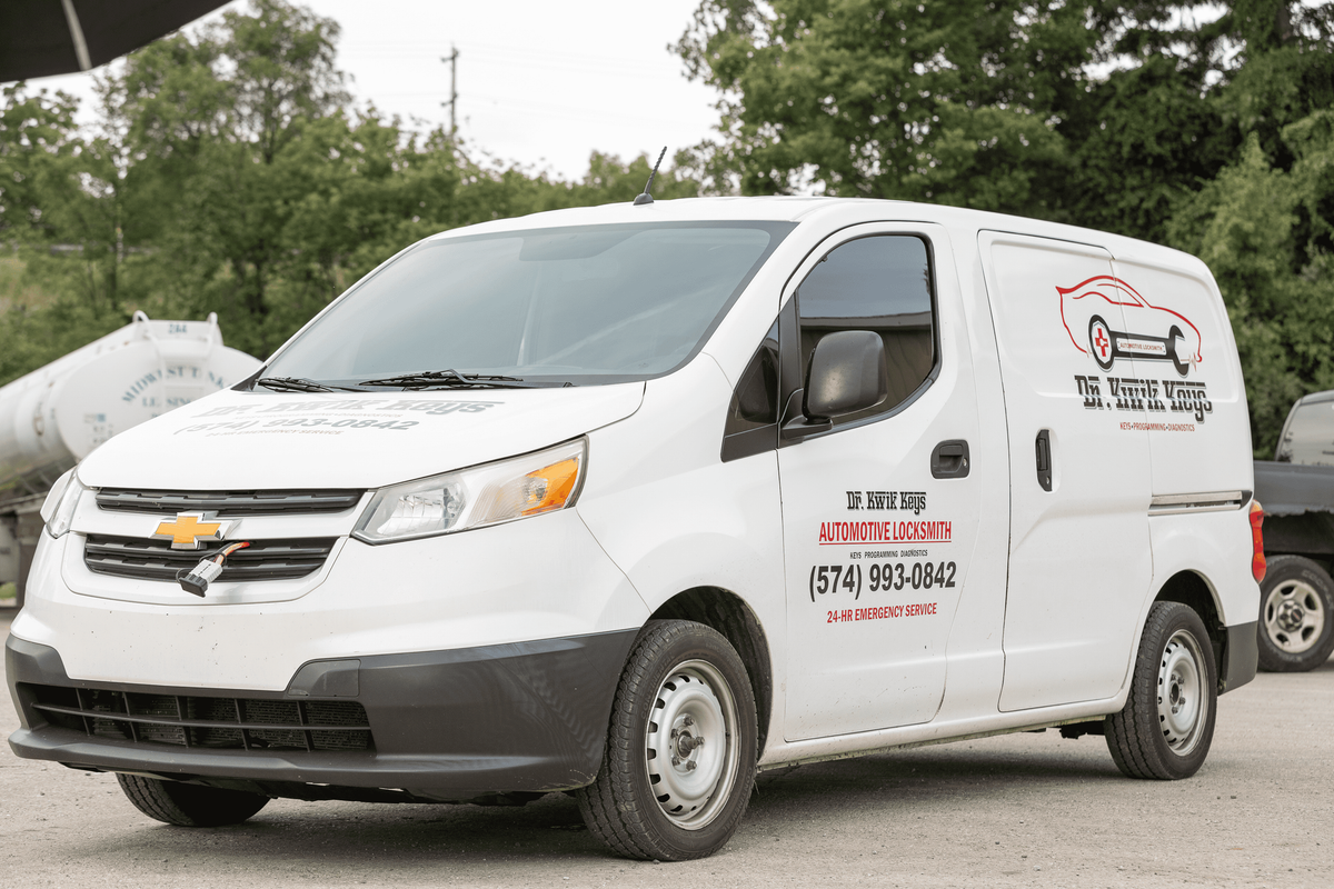 A white van is parked in a gravel lot.