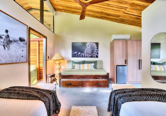 Bedroom with two twin beds, daybed, framed art, wood ceiling, neutral tones.