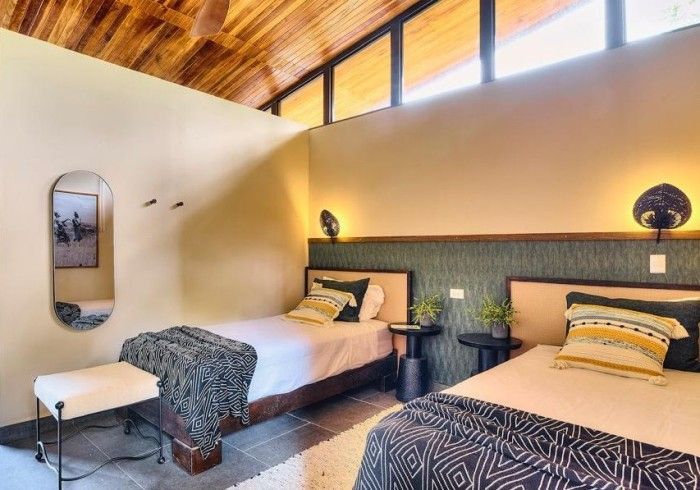 Two twin beds in a room with a wooden ceiling, neutral walls, and decorative accents.