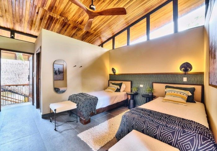 Bedroom with two twin beds, wooden ceiling, and neutral walls.