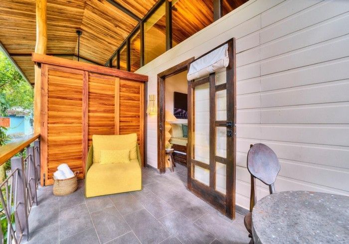 Balcony with wooden accents, yellow chair, open door to interior, stone table, light gray flooring.